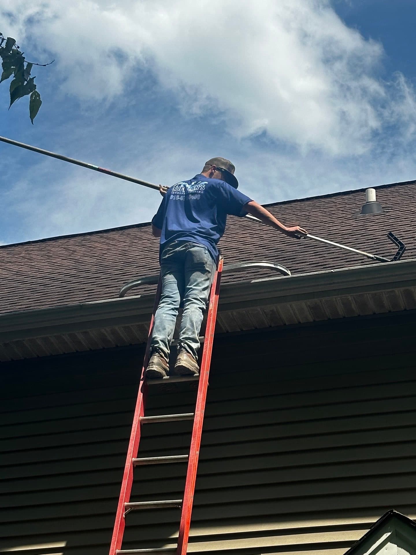Technician on ladder performing professional gutter cleaning in Franklin, TN